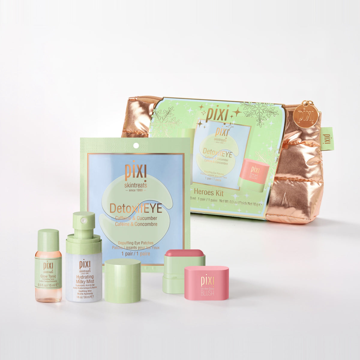 Pixi Heroes Kit skincare set on a clean white background, featuring a metallic rose gold zippered pouch, a light green sachet, a small pink jar, a light green bottle, and other matching skincare containers.