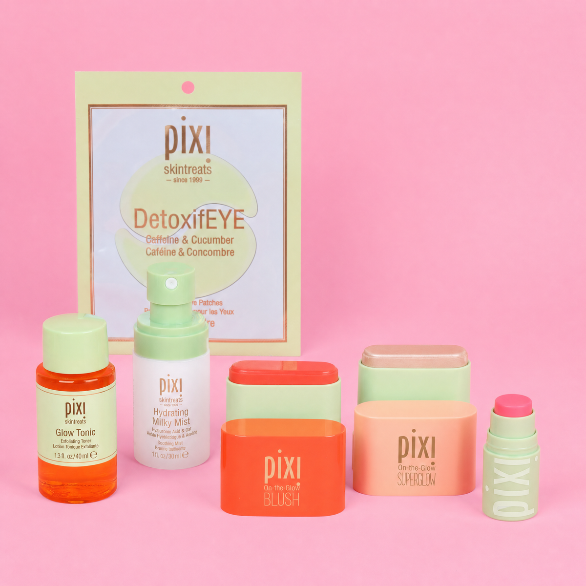 A Pixi skincare set arranged on a pink background, including a DetoxiFYE eye patch single pair, Glow Tonic, Hydrating Milky Mist, On-the-Glow Blush Petite, On-the-Glow SuperGlow Petite and +HydraLipTreats Petite.