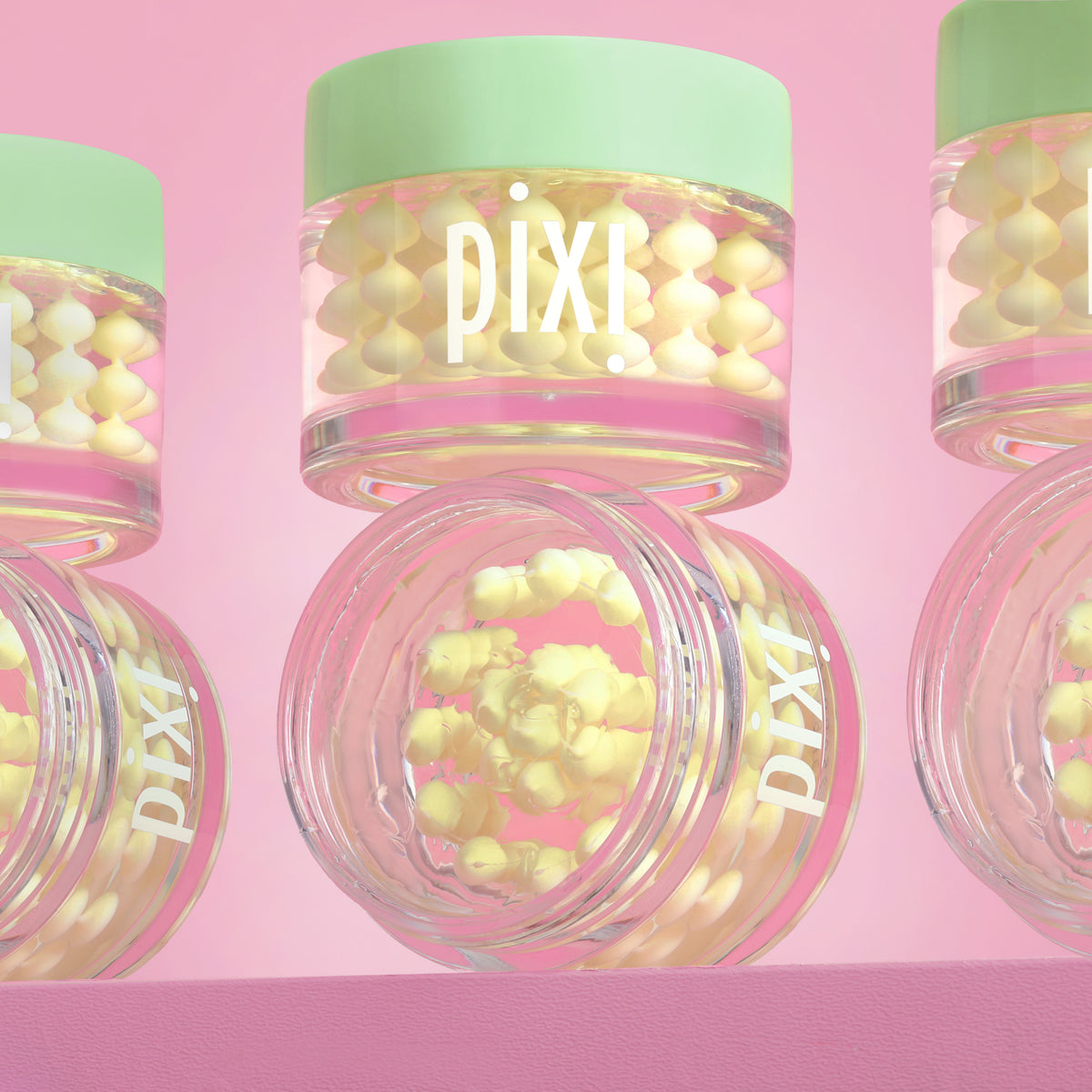 Pixi Vitamin-C CreamSerum product with pink lid and green cap on a pink background - several jars in view